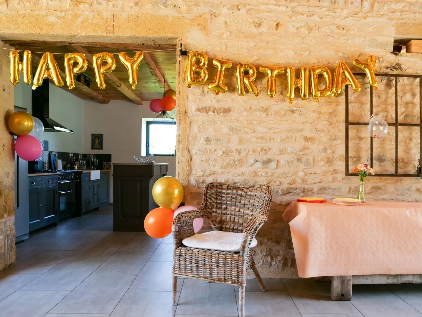 Une guirlande de ballons Happy Birthday dans la cuisine ouverte sur la salle
