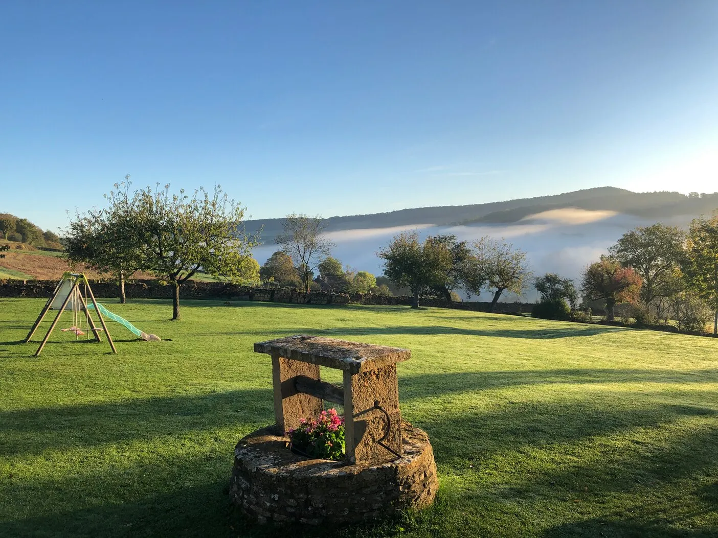 Le puits dans le jardin, la brume dans la vallée au petit matin
